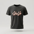A dark charcoal gray short-sleeve t-shirt with stylized Arabic calligraphy printed across the chest in white with a pinkish-red shadow, shown against a light gray background.