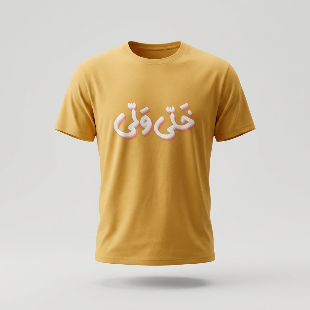 A mustard yellow short-sleeve t-shirt with Arabic calligraphy printed across the chest in white with a pink shadow effect, shown against a light gray background.